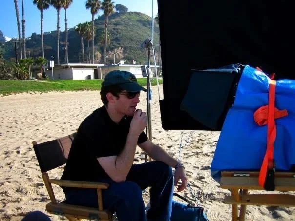 A production moment on the beach, with David Price using a radio beside a shaded monitor.