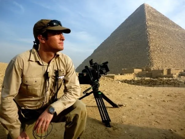 David Price beside a camera with a pyramid in the background during Chasing Mummies production.